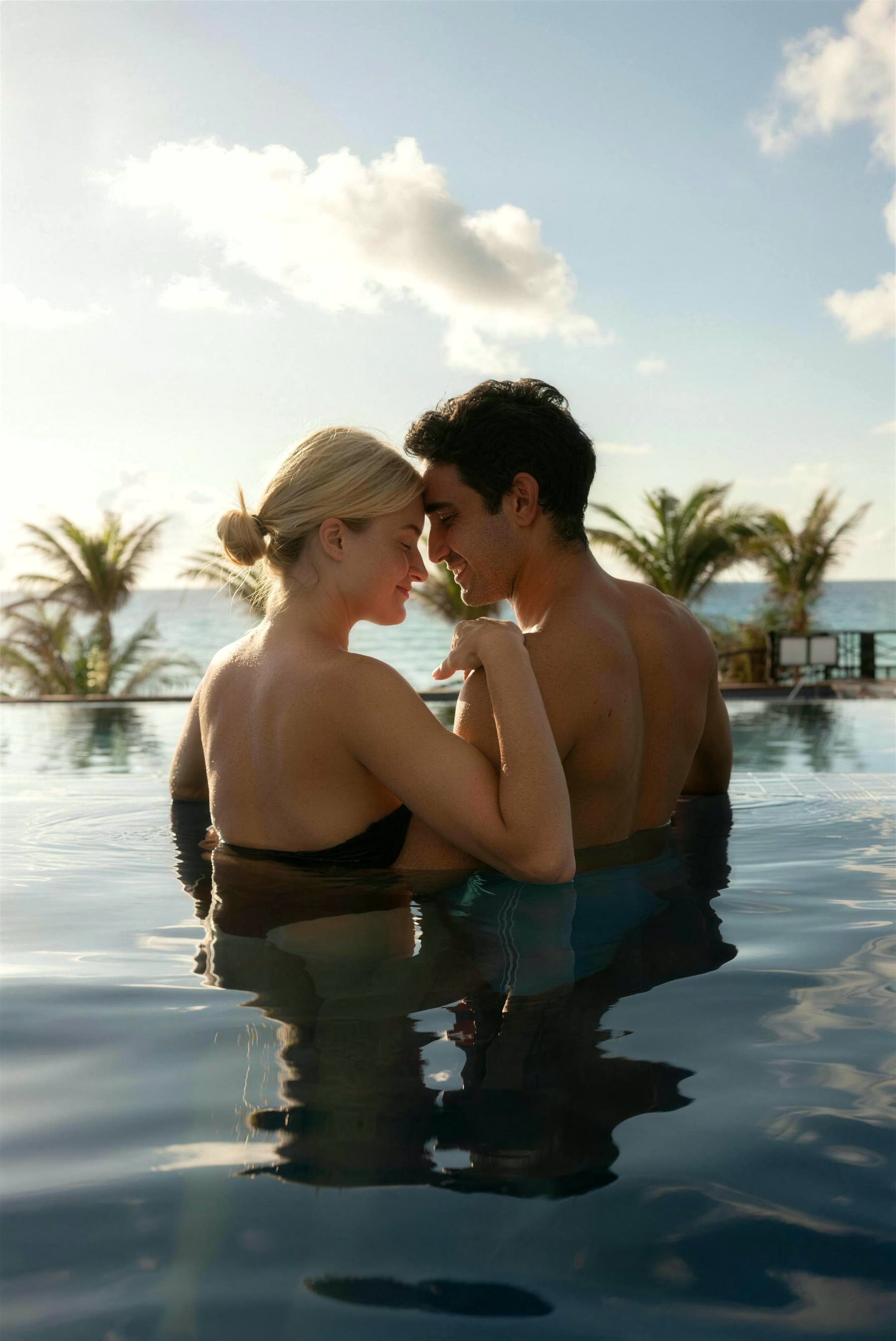 Casal na piscina de borda infinita de frente para o mar